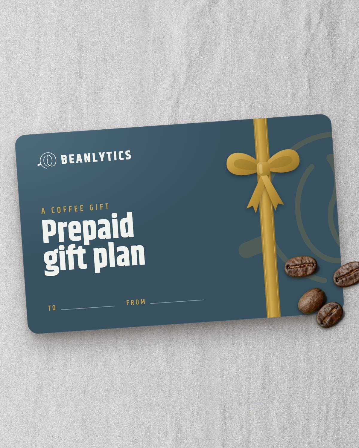 Prepaid gift plan card printed with a gold ribbon and bow, coffee beans resting on its corner