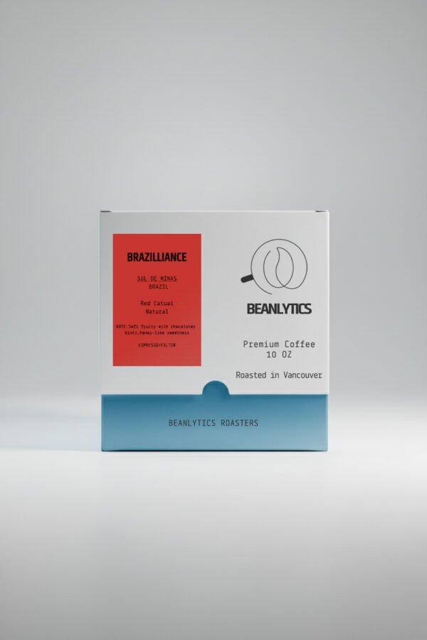 Front view of a Beanlytics Roasters coffee box featuring the “Brazilliance” Brazil Sul de Minas Red Catuai Natural coffee. The white box has a red label on the left with tasting notes and a Beanlytics logo on the right, with “Premium Coffee 10 oz – Roasted in Vancouver” printed below.