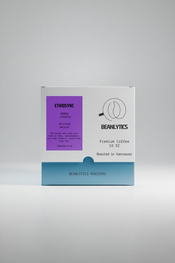 Front view of a Beanlytics Roasters 10 oz coffee box featuring the “Ethiosync” Ethiopia Oromia Heirloom natural coffee. The label is deep berry purple with black text detailing tasting notes of taffy, ripe blueberry, dried cranberry, and cocoa nibs. The box base is light blue with the Beanlytics Roasters logo and “Roasted in Vancouver” printed on the front.